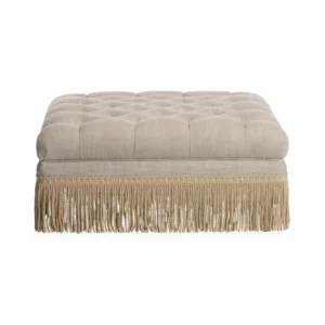 Beige tufted ottoman with fringe detailing.