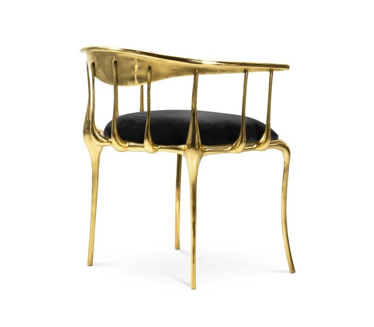 Gold modern chair with black cushioned seat.
