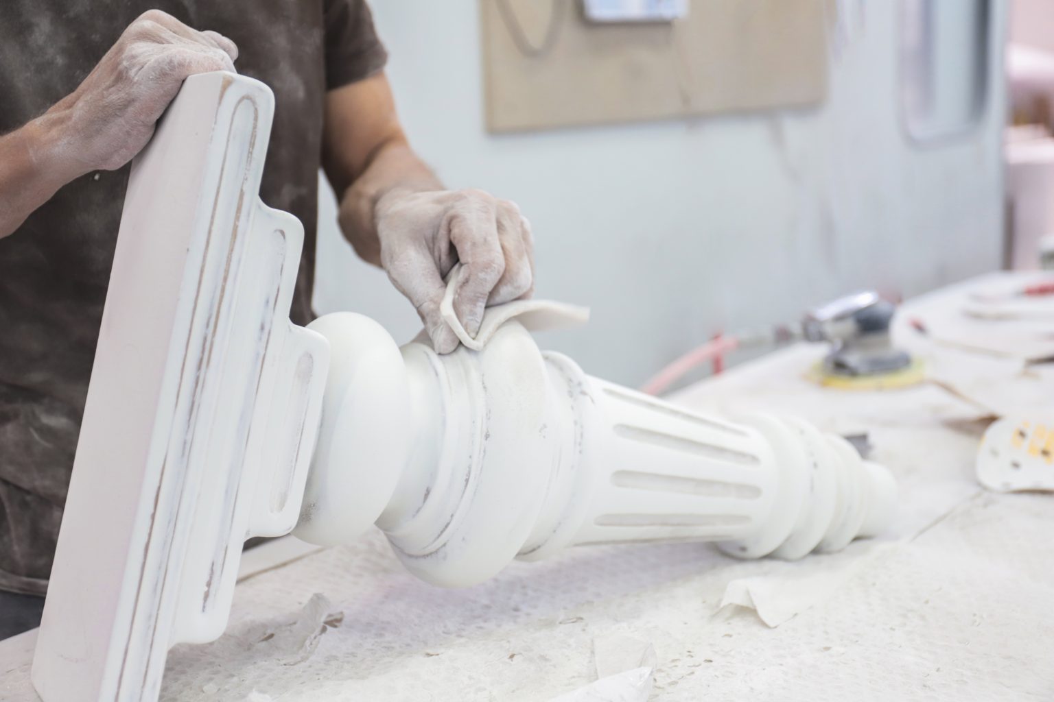 Craftsman polishing architectural column piece in workshop.