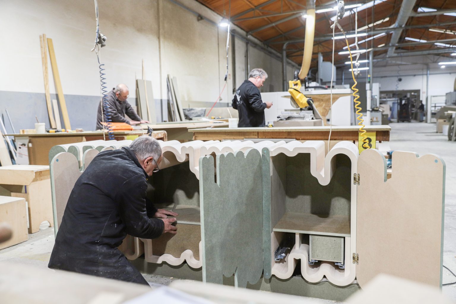 Carpenters working on custom wooden furniture in workshop.