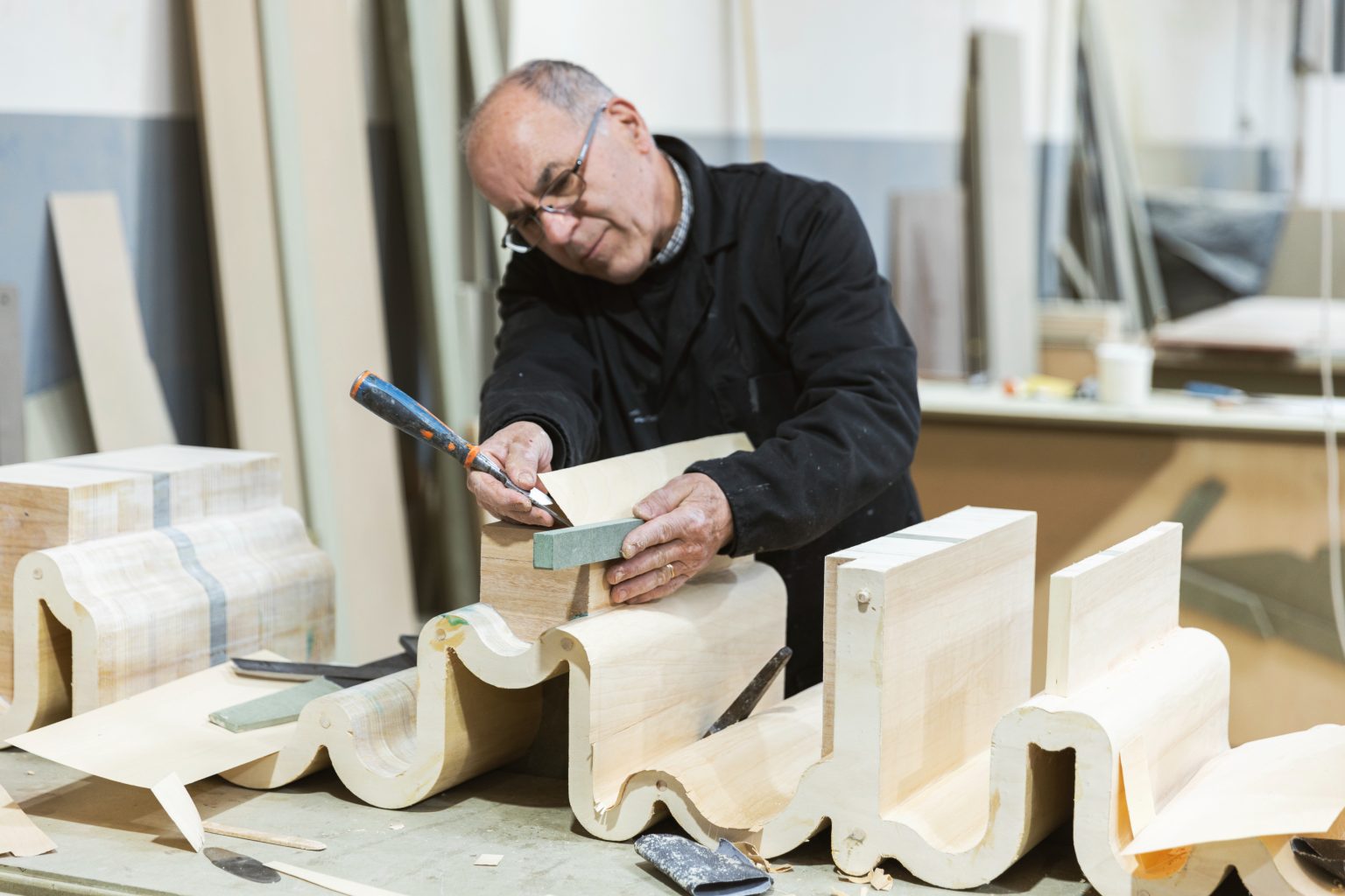 Carpenter crafting wooden moulding with precision tools.