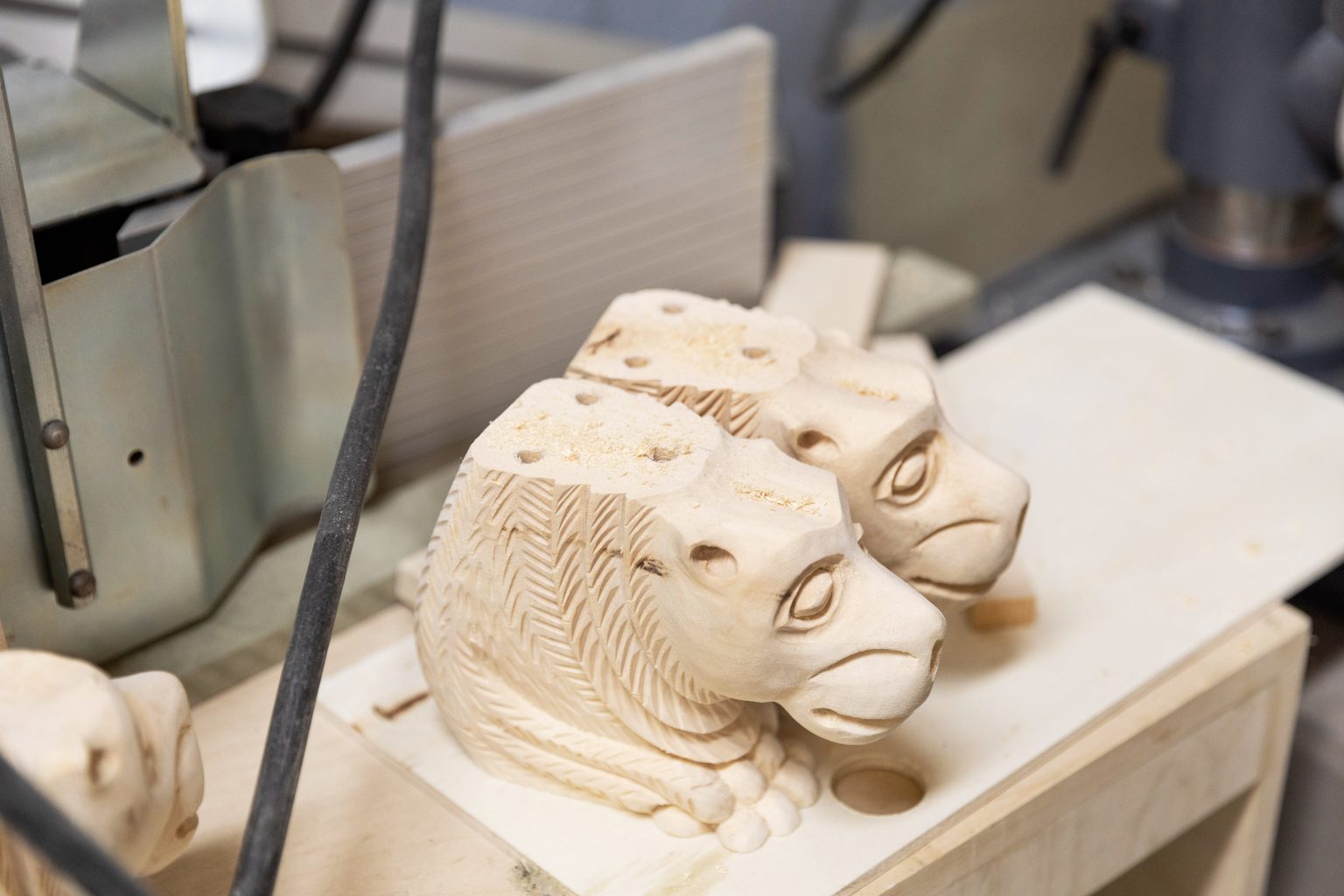 Wooden lion carvings on workshop table.